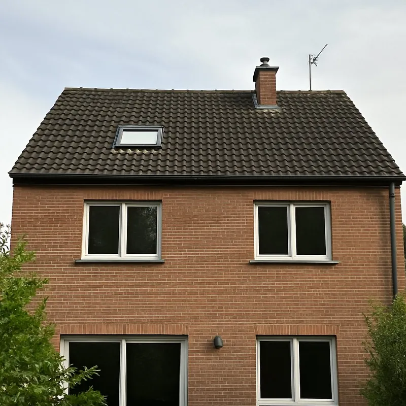 Maison en brique avec fenêtre de toit posée dans une toiture en tuiles sombres