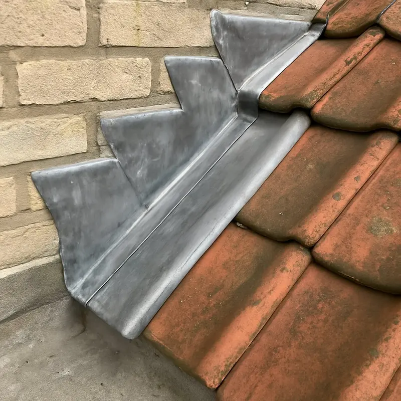 Solin en zinc à gradins entre un mur en briques et une toiture en tuiles